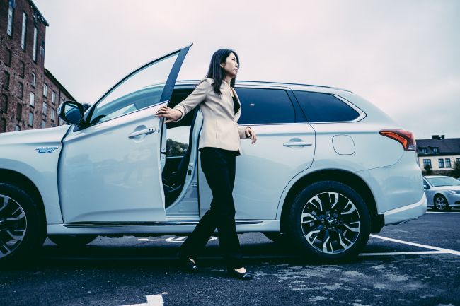 Aasialainen nainen nousee hopeisesta autosta ABAXin toimiston pihalla